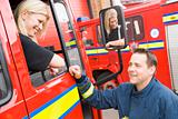 Firefighter sitting in the cab of a fire engine talking to a co-