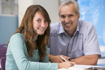 A teacher instructs a schoolgirl in a high school class
