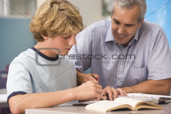 A teacher instructs a schoolboy in a high school class