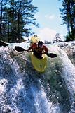 Young man kayaking down waterfall
