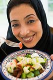 A Middle Eastern woman with a plate of salad