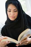 A middle eastern woman reading a book
