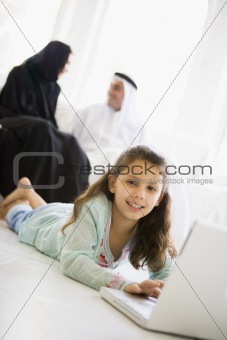 A Middle Eastern girl lying on the floor using a laptop