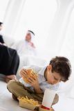 A Middle Eastern boy enjoying a fast food burger meal