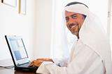 A Middle Eastern man sitting in front of a computer at home