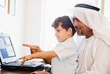 A Middle Eastern man and his son sitting in front of a computer 
