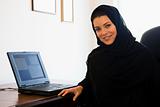 A Middle Eastern woman sitting in front of a computer at home