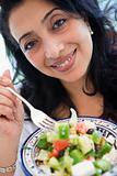 A Middle Eastern woman holding a salad up to the camera