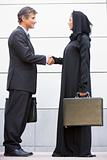 A caucasian businessman and Middle Eastern woman shaking hands