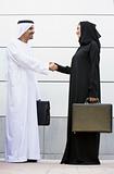 A Middle Eastern businessman and woman shaking hands