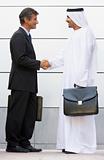 A Middle Eastern and a caucasian businessman shaking hands