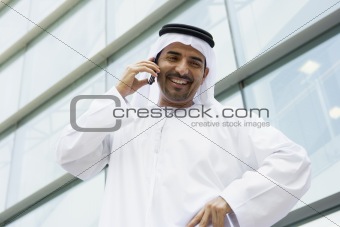 A Middle Eastern businessman talking on the phone outside an off