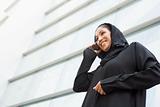 A Middle Eastern businesswoman talking on the phone outside an o