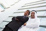 A Middle Eastern businessman and Caucasian man standing outside 