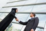 A Middle Eastern businesswoman and a Caucasian man shaking hands