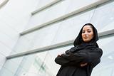 A Middle Eastern businesswoman standing outside an office block