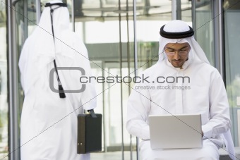 A Middle Eastern businessman sitting with a laptop