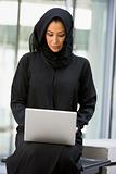 A Middle Eastern business woman sitting with a laptop