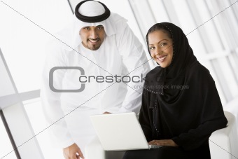 A Middle Eastern businessman talking to a woman using a laptop