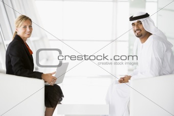 A Middle Eastern man and caucasian woman talking at a business m