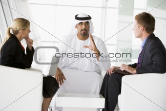 A Middle Eastern man and a caucasian man and woman talking at a 