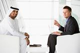 A Middle Eastern man and a caucasian man talking at a business m