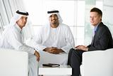 Two Middle Eastern men and a caucasian man talking at a business