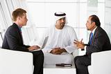 Two Middle Eastern men and a caucasian man talking at a business