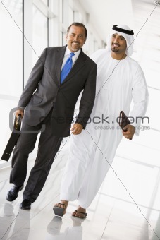 Two Middle Eastern businessmen walking in a corridor