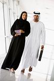 A Middle Eastern businessman and woman walking in a corridor