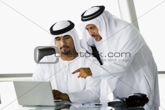 Two Middle Eastern businessmen beside a laptop