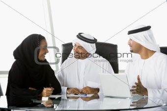 Two Middle Eastern businessmen and a woman beside a laptop