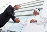 A Middle Eastern businessman shaking hands with a Caucasian busi