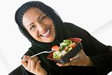 A Middle Eastern woman holding a salad up to the camera