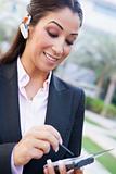 Businesswoman using bluetooth earpiece and PDA