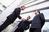 Group of businessmen shaking hands outside office