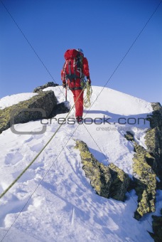 Young man mountain climbing on snowy peak