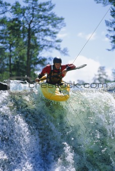 Young man kayaking on waterfall