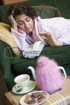 A young woman lying on her couch watching the telephone