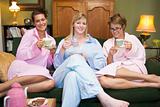 Three young women drinking tea together in their pyjamas