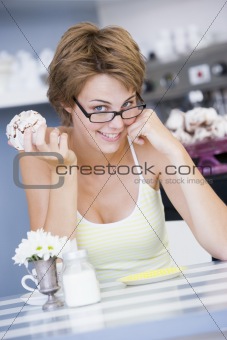 A young woman sitting in a cafe eating a sweet treat