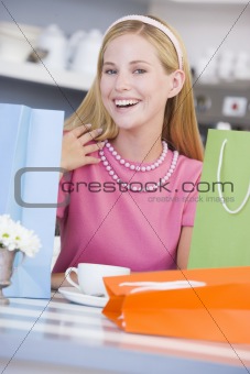 A young woman sitting in a cafe with shopping bags