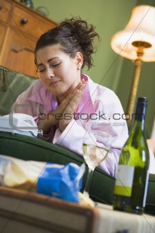 A young woman in her pyjamas drinking wine and watching her tele