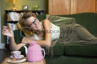 A young woman lying on her couch eating biscuits