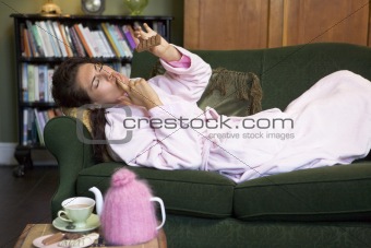 A young woman lying on her couch eating chocolate