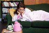 A young woman lying on her couch watching the phone