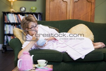 A young woman lying on her couch eating cereal