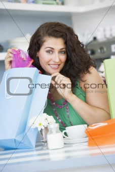 A young woman with shopping bags sitting in a cafe