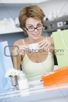 A young woman sitting in a cafe with shopping bags drinking tea