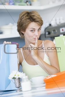 A young woman sitting in a cafe with shoping bags